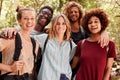 Five millennial friends on a hiking trip in a forest smiling to camera, waist up, close up