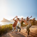 Five millennial friends on a road trip have fun posing for photos on a coastal path, full length