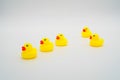 Five mini yellow rubber ducks in a row. One duck making their wa