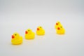 Five mini yellow rubber ducks in a row. One duck out of line. Ge