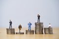 Five Miniature figure in each career standing to different high and low coins stacking for variation of income or salary in each Royalty Free Stock Photo