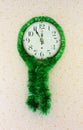 Five minutes to twelve on old wall clock decorated with green tinsel Royalty Free Stock Photo