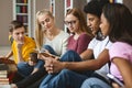 Five classmates reading lecture notes, sitting on library floor