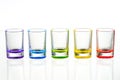 Five multicolored empty shot glasses placed symmetrically on a w Royalty Free Stock Photo