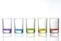 Five multicolored empty shot glasses placed symmetrically on a w Royalty Free Stock Photo