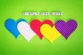 Five multicolored valentine hearts and the inscription Simply The Love made of white alfphabet cubeson a green background