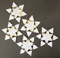 Five origami star snowflakes in white and gold foil paper, on a dark grey paper background Royalty Free Stock Photo