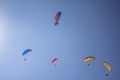 Five paragliders on colored parachutes fly against the background of clean blue sky and the sun Royalty Free Stock Photo