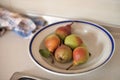 Five pears in a plate with a blue border and a kitchen towel on the table Royalty Free Stock Photo