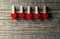 Five pegs with red heart hanging on the rope on wooden backdrop. Happy valentines day