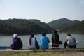 Five people sit near the lake in mountains
