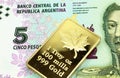 A five peso banknote from Argentina with a gold coin in macro
