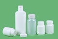 Five pills bottles on green background with copy space for text. Pharmaceutical product container. Pharmacy remedy