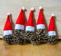 Five pine cones in a red Santa hats like a Christmas tree on a wooden background Royalty Free Stock Photo