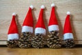 Five pine cones in a red Santa hats like a Christmas tree on a wooden background Royalty Free Stock Photo
