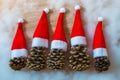 Five pine cones in a red Santa hats like a Christmas tree on a wooden background Royalty Free Stock Photo