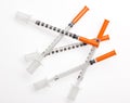 Five plastic syringes with needles closed by protective caps