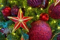Five-pointed red star with a golden border on the Christmas tree with garlands. Royalty Free Stock Photo