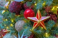Five-pointed red star with a golden border on the Christmas tree with garlands. Royalty Free Stock Photo