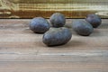 Five potatoes of purple variety Violetta on wood in front of a wooden box Royalty Free Stock Photo