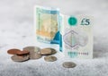 Five pounds banknote with coins on light background. Economy crisis concept