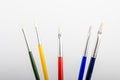 Five professional artist paintbrushes displayed horizontally isolated on a white studio paper