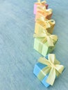Five rainbow gradient colors square gift boxes arranged in a diagonal row on a blue-green watercolor textured background, vertical Royalty Free Stock Photo