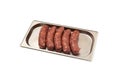 Five raw sausages for barbecue grill on metal tray. Natural meat processed foods. Frankfurters. White background. Selective focus