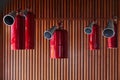 Red fire extinguishers hanging on ropes on a wooden wall background Royalty Free Stock Photo