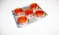 Five red round jelly tablets in a gray package on a light background during the coronavirus Royalty Free Stock Photo