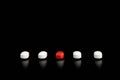 Five red and white pills on a black background
