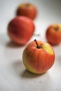 Five ripe apples, red with yellow spots, lie on a white table Royalty Free Stock Photo