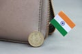 Five Rupee money coin of India and mini Indian flag stick on the leather wallet on grey background