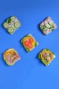 Five sandwich with avocado, radish, cucumber, raw ham, pepper and fresh cheese on a blue background, top view Royalty Free Stock Photo