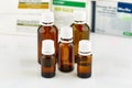 Five small brown medicine phials with pills packs on background.