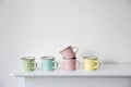 FIVE small multicolored pastel coffee cups on a white console against a wall background Royalty Free Stock Photo