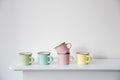 FIVE small multicolored pastel coffee cups on a white console against a wall background Royalty Free Stock Photo