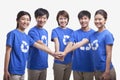 Five smiling and happy young people in a row wearing recycling symbol t-shirts with hands together, studio shot