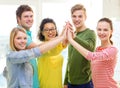 Five smiling students giving high five at school