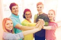 Five smiling students giving high five at school