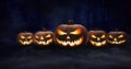 Five spooky halloween pumpkin, Jack O Lantern, with an evil face and eyes on the forest floor. Royalty Free Stock Photo