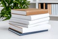 Five Stacked Books on Table with Green Plant Background in Modern Office Setting Royalty Free Stock Photo