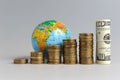 Five stacks of coins with a globe and a bundle of dollars Royalty Free Stock Photo