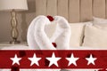 Five Star Luxury Hotel. Beautiful swans made of towels decorated with red roses on bed in five star hotel room Royalty Free Stock Photo