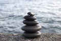 Five stones cairn tower, rock zen sculpture, black pebbles and ocean light blue background