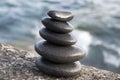 Five stones cairn tower, rock zen sculpture, black pebbles and ocean light blue background