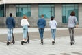 Five students having ride on motorized kick e-scooters