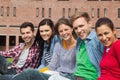 Five students sitting on the grass smiling at camera