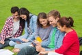 Five students sitting on the grass using tablet