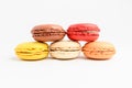 Five sweet French macarons with different aromas, isolated on white, flavours of strawberries, lemon, caramel, vanilla, orange and